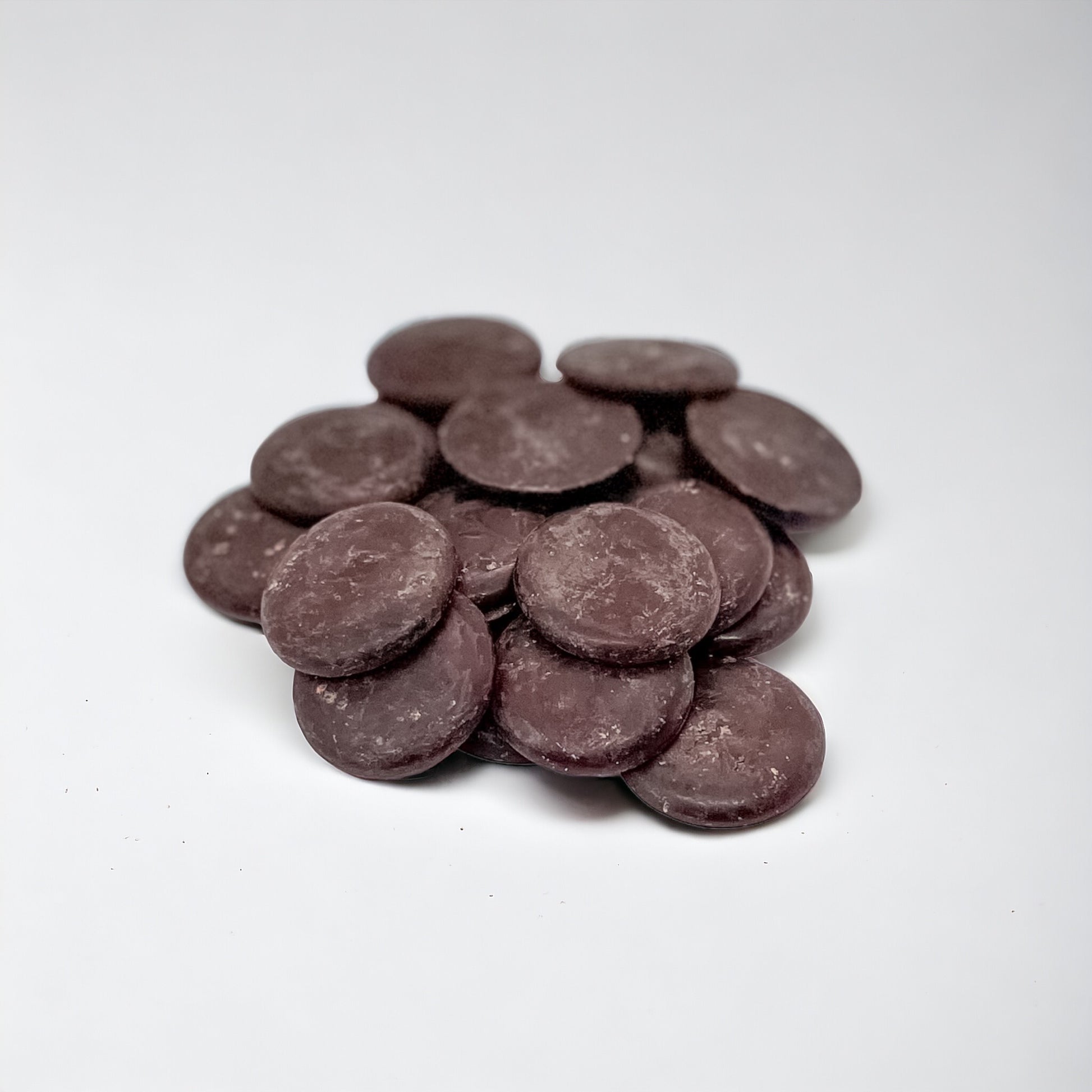 A pile of rich, dark cacao Liquor paste buttons, highlighting their smooth, round shape and deep chocolate color, ideal for culinary and confectionery applications.